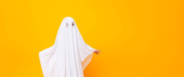 Little kid wearing cute halloween ghost costume on yellow background. - Φωτογραφία, εικόνα