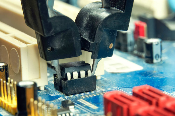 Egy mérnök eltávolít egy programozható BIOS chipet fogóval - Fotó, kép