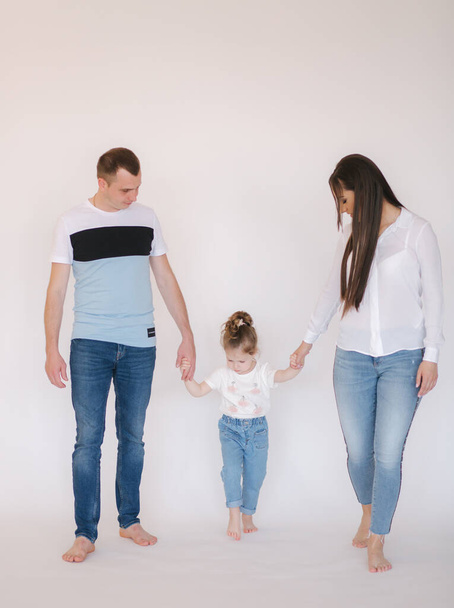 Mom dad and daughter walking in studio. White background - Photo, Image