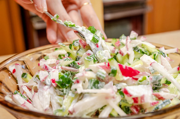female hands are mixed with a spoon of vegetable salad with mayonnaise close-up - Photo, Image