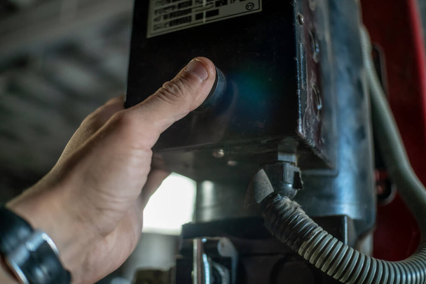 Мужская рука крупным планом нажимает кнопку подъема в промышленных помещениях - Фото, изображение