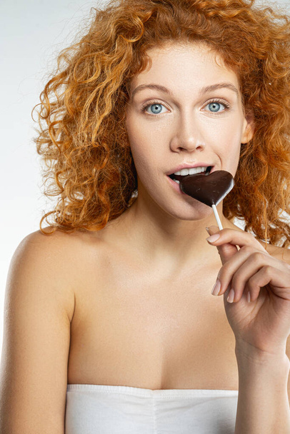 Beautiful woman biting into heart shaped chocolate - Foto, immagini