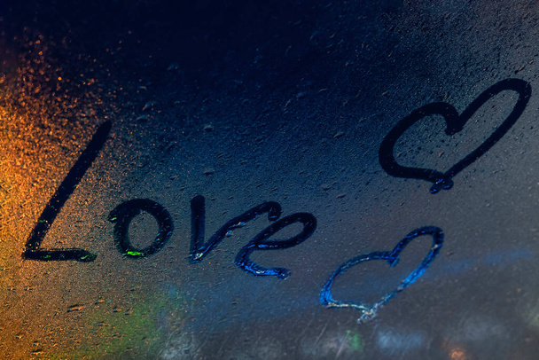 inscriptie Liefde op misted glas, nachtlampjes bokeh op de achtergrond - Foto, afbeelding