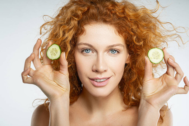 Happy young female with slices of cucumber in hands - Foto, afbeelding