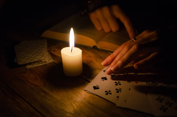 Cartes, un livre, une bougie, une main sur une table en bois. étude de la magie. concept de divination, magie. - Photo, image