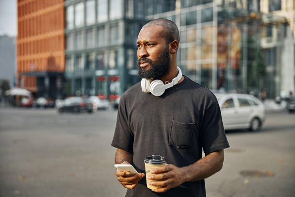 Calm bearded man in the city with gadget and coffee - Photo, Image
