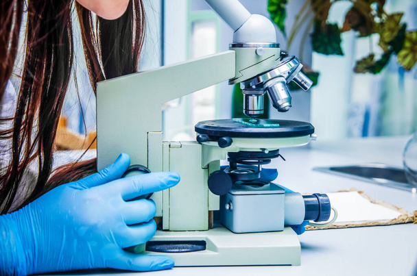 γυναίκα επιστήμονας κοιτάζει μέσα από ένα μικροσκόπιο σε ένα εργαστήριο. Έννοια της επιστήμης, της ιατρικής - Φωτογραφία, εικόνα