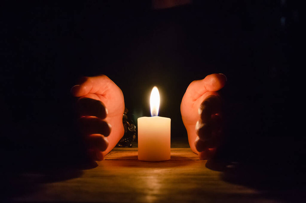 Mani avvolte intorno a una grande candela primo piano, copia lo spazio - Foto, immagini