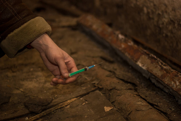 Contra o tema do abuso de drogas, visão de mãos masculinas com uma seringa de drogas, no porão, problema mundial de drogas - Foto, Imagem