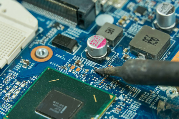 master repairs the motherboard using a soldering iron close up - Photo, image