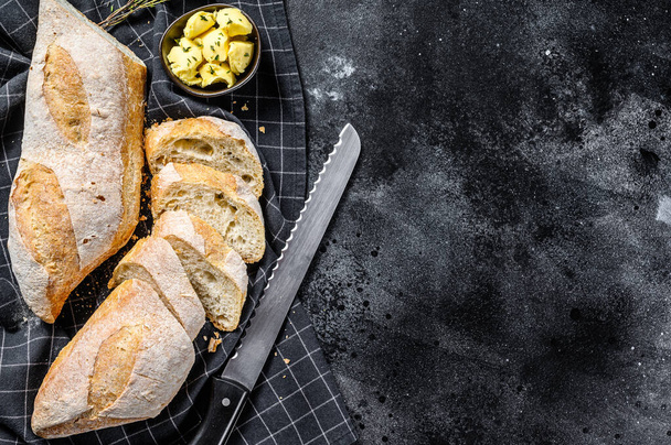 Artisanal baguettes and cut slice with butter. black background. top view. Copy space. - Photo, Image