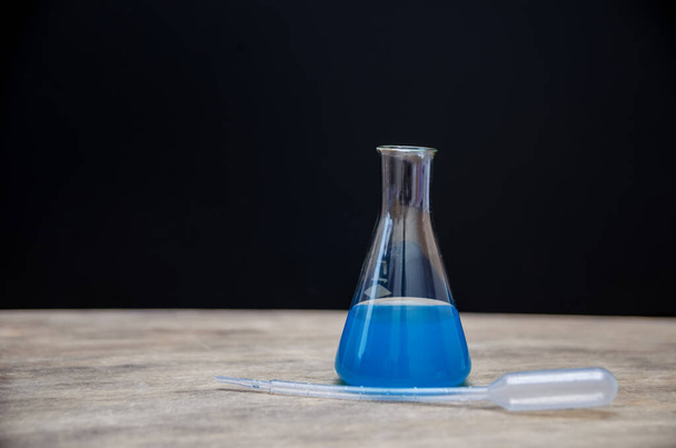 Χημική φιάλη με μπλε εργαστηριακές χρωστικές ουσίες μέσα σε μαύρο φόντο. Η έννοια της εμπειρογνωμοσύνης και της ιατρικής. - Φωτογραφία, εικόνα