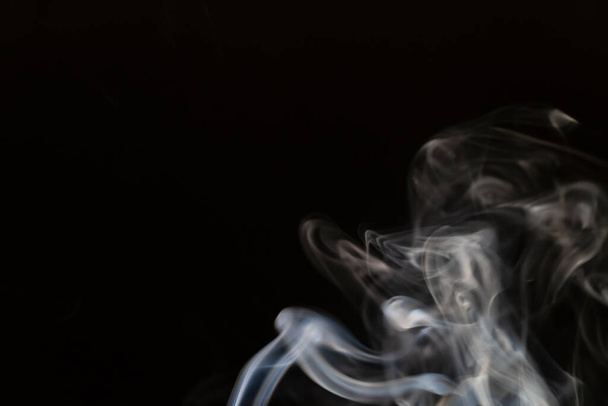 Fondo de humo abstracto con espacio de copia sobre fondo negro. Humo azul-blanco saliendo de la varilla de incienso - Foto, imagen