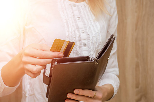 Γυναίκα χέρι τραβά έξω ή βάζει μια πιστωτική κάρτα από το πορτοφόλι. Φωτογραφίες με φωτοβολίδα. - Φωτογραφία, εικόνα