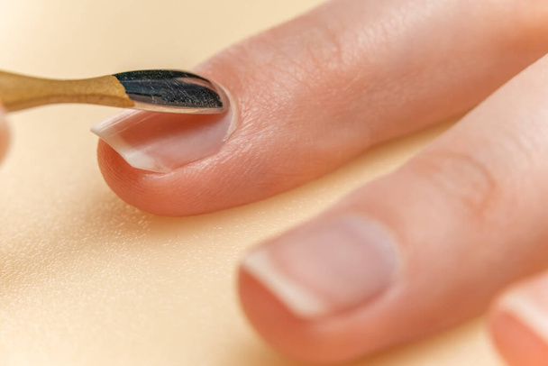 A rapariga faz a sua própria manicura. A remoção de cutícula de um dedo fecha - Foto, Imagem