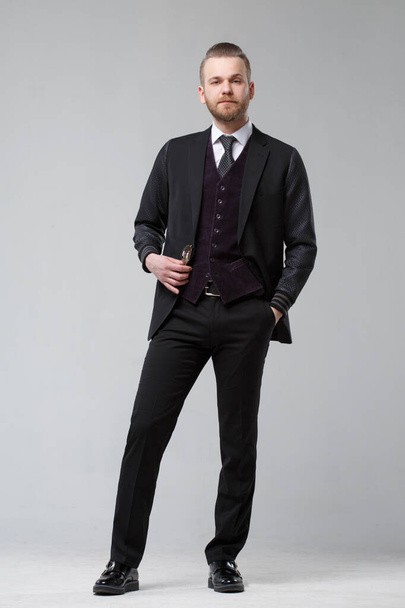 Elegant man in a three-piece suit stands in full growth on a gray background. - Foto, Imagem