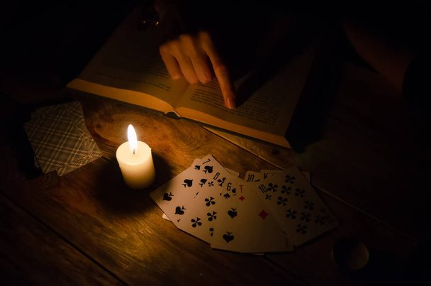 Cartões, um livro, uma vela, uma mão numa mesa de madeira. estudo da magia. conceito de adivinhação, magia. - Foto, Imagem