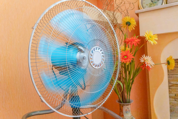 Close up on working electric floor standing fan in the modern house in sunny hot summer day. - Фото, изображение