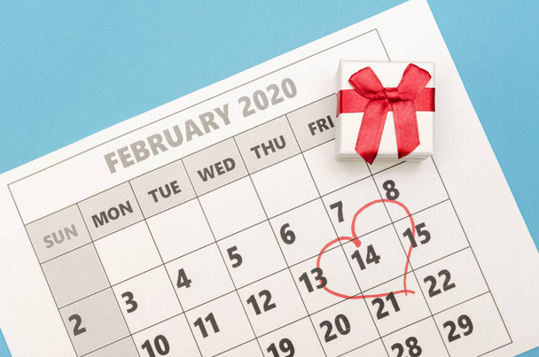 El día de San Valentín está marcado con un corazón en el calendario, hay una caja con un anillo al lado. Concepto de San Valentín, día festivo - Foto, Imagen