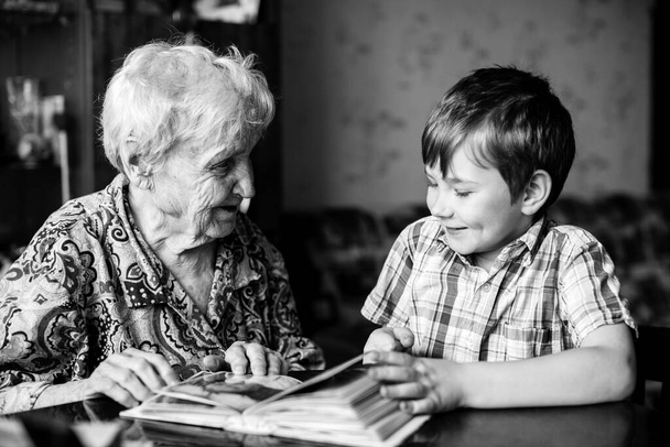 An old woman sits with his grandson with book. Black and white photo. - Photo, Image