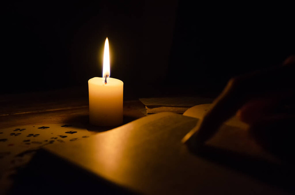 Κάρτες, ένα βιβλίο, ένα κερί, ένα χέρι σε ένα ξύλινο τραπέζι. μελέτη της μαγείας. έννοια της μαντείας, μαγεία. - Φωτογραφία, εικόνα