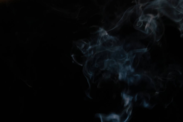 Abstrakter Rauchhintergrund mit Kopierraum auf schwarzem Hintergrund. Blau-weißer Rauch steigt vom Räucherstäbchen auf - Foto, Bild