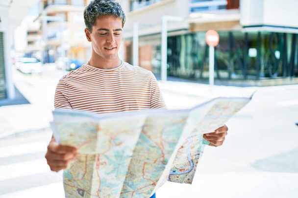 Jeune homme de tourisme caucasien beau regardant la carte de la ville à la rue - Photo, image