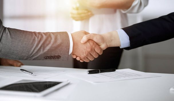 Business people shaking hands finishing contract signing in sunny office, close-up. Handshake and marketing - Foto, Imagem