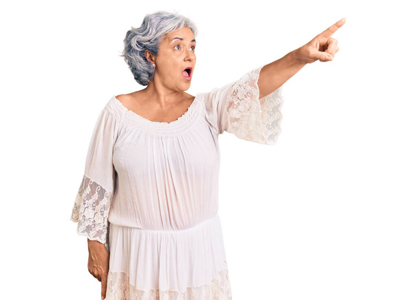 Seniorin mit grauen Haaren trägt Bohemian-Stil zeigt mit dem Finger überrascht voraus, offenen Mund erstaunte Miene, etwas auf der Vorderseite  - Foto, Bild