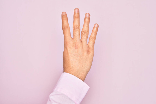 Hand eines kaukasischen jungen Mannes mit Fingern über isoliertem rosa Hintergrund, Zählzahl 4 mit vier Fingern - Foto, Bild