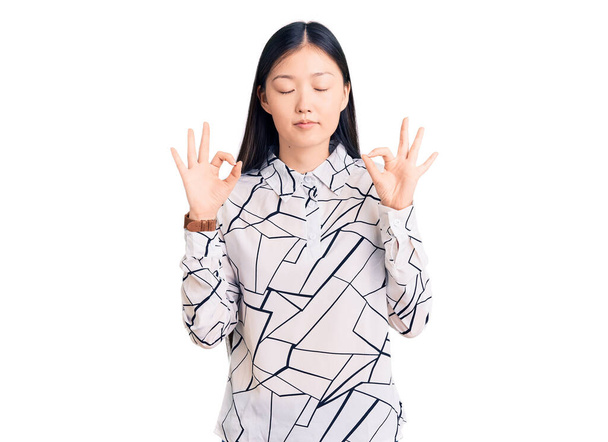Young beautiful chinese woman wearing casual shirt relaxed and smiling with eyes closed doing meditation gesture with fingers. yoga concept.  - Фото, зображення