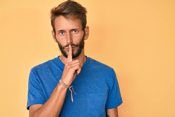 Handsome caucasian man with beard wearing casual clothes asking to be quiet with finger on lips. silence and secret concept.  - Photo, Image