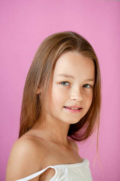 egy kedves, 9 éves, hosszú hajú lány portréja egy orgonafalnak támasztva. - Fotó, kép