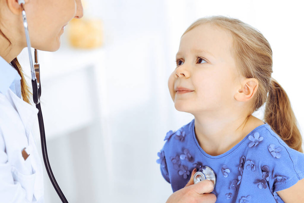 Lekarz badający małą dziewczynkę stetoskopem. Szczęśliwy, uśmiechnięty pacjent na zwykłej inspekcji medycznej. Medycyna i koncepcje opieki zdrowotnej - Zdjęcie, obraz