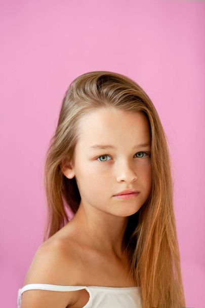 egy kedves, 9 éves, hosszú hajú lány portréja egy orgonafalnak támasztva. - Fotó, kép