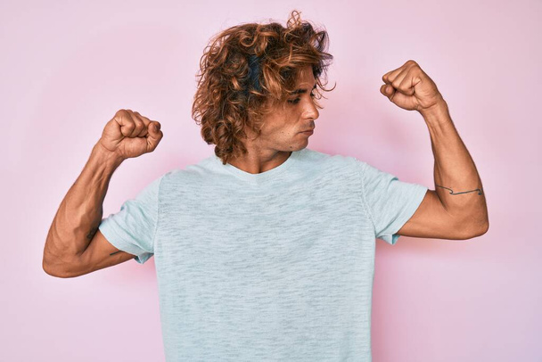 Jonge Latijns-Amerikaanse man in casual kleding met armen spieren glimlachend trots. fitness concept.  - Foto, afbeelding