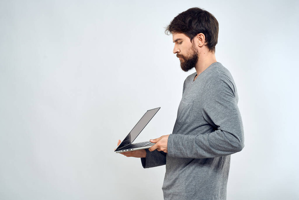 Un homme dans un pull gris avec un ordinateur portable mains style de vie technologie communication internet travail - Photo, image