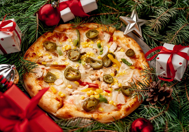 チキンフィレ、モッツァレラチーズ、ハラペーニョペッパー、トマト、玉ねぎ、コーン、クリスマスの装飾、贈り物、スプルース、おもちゃと鐘のピーマンとクリスマスのためのメキシコのピザ - 写真・画像