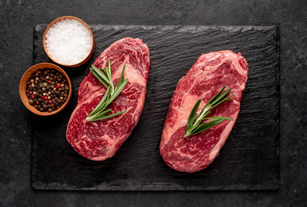 Deux steaks de côtelette de bœuf cru avec des épices sur fond de pierre - Photo, image