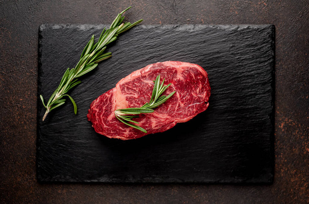 Nyers márványos marhahús fűszerekkel a háttér kövön - Fotó, kép
