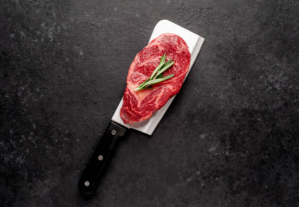 石の背景に肉のナイフで生の霜降り牛ステーキ - 写真・画像