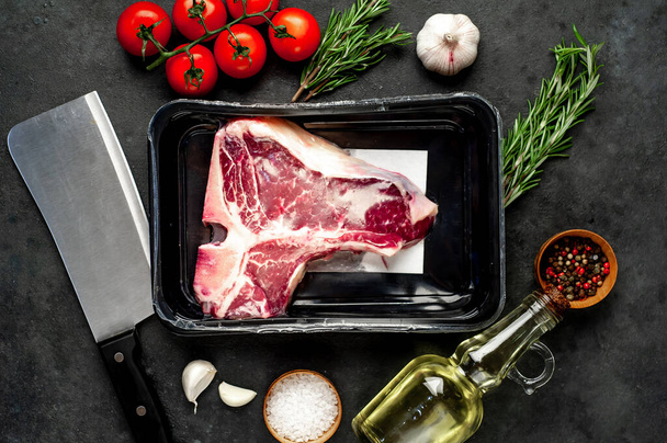 closeup view of raw t-bone steak with ingredients on stone background - Photo, Image