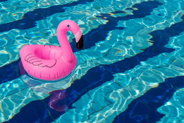 Odcisk flaminga. Różowy dmuchany flaming w wodzie basenowej na letnie tło plaży. Minimalna koncepcja lata - Zdjęcie, obraz