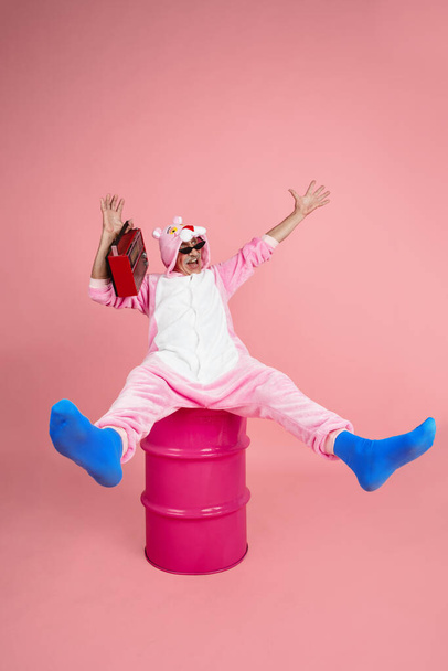 Senior hipster man in stylish pink attire isolated on pink background. Tech and joyful elderly lifestyle concept - Fotografie, Obrázek