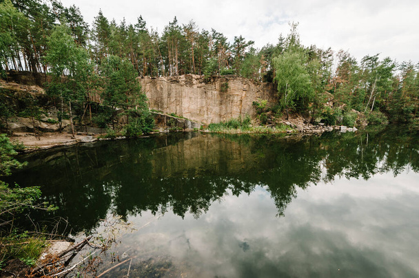 Landscape of an old flooded industrial granite quarry filled with water. Lake on the background of rocks and fir trees. Canyon The nature of the autumn. Place for text and design. - Zdjęcie, obraz