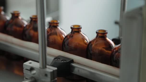 Barna injekciós üvegek szállítószalagon egy gyógyszergyártó üzemben. - Felvétel, videó