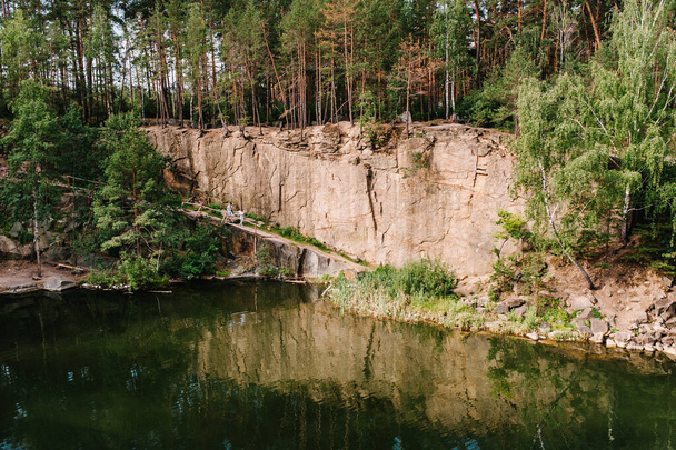 Landscape of an old flooded industrial granite quarry filled with water. reflected people in lake on the background of rocks and fir trees. Canyon. The nature of autumn. Place for text and design. - Foto, afbeelding