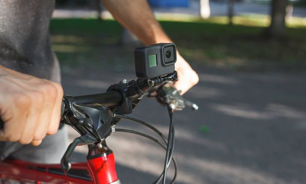 Action camera mounted on the handlebar of a bicycle that a male cyclist is holding - Foto, afbeelding