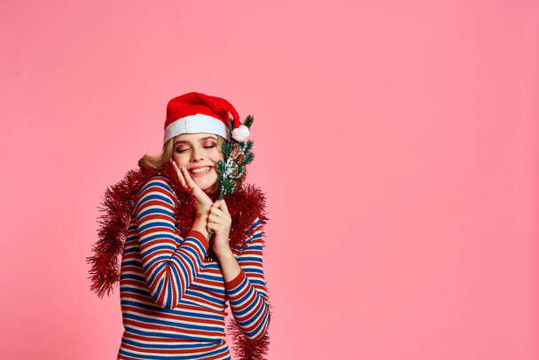 Nainen joulukuusi oksat käsissä punainen sävy ja juhlava hattu vaaleanpunainen tausta rajattu näkymä - Valokuva, kuva
