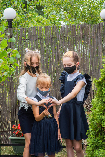 Három iskolás lány maszkot visel és visszamegy az iskolába a Covid-19-es járvány idején. Három iskoláslány védőmaszkot visel. Vírus, baktérium, iskola, védelem. Tini lányok iskolai egyenruhában. - Fotó, kép
